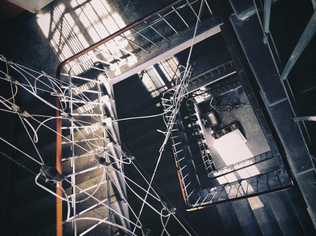 Aerial view of an industrial stairwell La gestion de l'énergie électrique représente un enjeu stratégique crucial pour les entreprises industrielles. Avec la montée des préoccupations environnementales, la nécessité de réduire les coûts énergétiques et l'évolution des technologies, une gestion efficace de l'énergie devient non seulement une exigence économique mais aussi une obligation écologique. Dans cet article, nous explorerons les meilleures pratiques, outils et stratégies pour optimiser la gestion de l’énergie électrique dans le cadre industriel. Les défis de la gestion de l'énergie dans les industries La gestion de l'énergie dans les entreprises industrielles n'est pas une tâche simple. Elle se confronte à plusieurs défis majeurs, tels que : La variabilité de la consommation énergétique : Les besoins en énergie d'une entreprise industrielle peuvent fluctuer en fonction des périodes de production, des saisons, des types d’équipements utilisés et des processus industriels. Les coûts croissants de l’énergie : L'augmentation des tarifs de l’électricité et des carburants, combinée à des marges bénéficiaires souvent serrées dans le secteur industriel, rend la gestion énergétique encore plus cruciale. Les contraintes réglementaires : De nombreuses entreprises sont désormais soumises à des législations strictes en matière d'efficacité énergétique et d'empreinte carbone, ce qui nécessite un suivi constant et des ajustements dans leur gestion énergétique. Pourquoi une gestion optimisée de l'énergie est essentielle ? Une gestion de l'énergie bien orchestrée offre de multiples avantages aux entreprises industrielles. Parmi les plus notables, on retrouve : Réduction des coûts d’exploitation L’optimisation de la consommation d'énergie peut générer des économies substantielles. Par exemple, l’intégration de technologies plus efficaces ou la mise en place de stratégies de réduction de la consommation pendant les périodes de pointe peut directement réduire les factures d’électricité. En outre, une analyse approfondie des profils de consommation permet d’identifier des pratiques énergétiques non rentables ou inutiles. Amélioration de l'empreinte carbone De nos jours, les entreprises industrielles sont sous pression pour réduire leur empreinte carbone. Une gestion énergétique efficace permet de réduire la consommation de ressources naturelles, contribuant ainsi à un avenir plus durable tout en respectant les normes environnementales. Renforcement de la compétitivité Une entreprise qui maîtrise ses coûts énergétiques dispose d’un avantage concurrentiel. En réduisant ses dépenses en énergie, elle pourra allouer davantage de ressources à l’innovation, à la recherche et au développement, ou encore à la réduction de ses prix, améliorant ainsi sa position sur le marché. Les étapes clés d’une gestion énergétique efficace dans l’industrie La mise en place d’un système de gestion de l’énergie (SGE) efficace nécessite une approche méthodique. Voici les étapes essentielles à suivre pour une gestion optimisée de l’énergie électrique dans les entreprises industrielles : 1. Évaluation de la consommation énergétique Avant toute chose, il est crucial de réaliser un diagnostic énergétique complet de l’entreprise. Cette première étape permet de comprendre comment et où l’énergie est utilisée. Les outils de mesure tels que les compteurs intelligents ou les systèmes de gestion énergétique permettent de collecter des données précises et d’identifier les zones de surconsommation. 2. Mise en place d’objectifs clairs Les objectifs doivent être définis de manière spécifique, mesurable, atteignable, réaliste et temporellement définis (SMART). Ces objectifs peuvent inclure des réductions de consommation, des investissements dans des équipements plus performants, ou l’intégration de sources d’énergie renouvelable dans le mix énergétique de l’entreprise. 3. Adopter des technologies innovantes L’innovation technologique joue un rôle central dans l’optimisation énergétique. L’introduction de systèmes de gestion d’énergie en temps réel, l’automatisation des processus industriels et l’optimisation de l’utilisation des équipements peuvent contribuer de manière significative à la réduction des gaspillages énergétiques. Parmi les technologies les plus performantes, on trouve : Les capteurs intelligents : Ces dispositifs permettent de suivre en temps réel la consommation d’énergie et d’identifier rapidement les dérives. Les variateurs de fréquence : Utilisés dans les moteurs industriels, ces équipements permettent de réguler la vitesse de rotation des moteurs et d’adapter ainsi la consommation d’énergie en fonction des besoins réels de production. L’Intelligence Artificielle (IA) : L’IA et l’analyse des données permettent d’optimiser en continu les processus énergétiques en prédisant les pics de consommation et en ajustant les paramètres des équipements en conséquence. 4. Mettre en place des actions de sensibilisation et de formation La formation des employés est un autre pilier de la gestion énergétique. En les sensibilisant aux bonnes pratiques de gestion de l’énergie (éteindre les équipements inutilisés, optimiser les processus, etc.), l’entreprise peut réaliser des économies substantielles. Les employés doivent également être formés à l'utilisation des outils de mesure et à la lecture des rapports énergétiques pour qu’ils puissent contribuer activement à l’optimisation. 5. Analyse et suivi continu La gestion de l'énergie n'est pas une démarche ponctuelle, mais un processus continu. Après la mise en œuvre des premières actions, il est essentiel de suivre régulièrement les résultats obtenus et de procéder à des ajustements. Des outils de reporting automatisés et des audits réguliers permettront d’identifier les progrès réalisés, tout en signalant les domaines nécessitant des améliorations. Les outils de gestion de l'énergie électrique Pour faciliter la gestion de l’énergie, plusieurs outils et systèmes peuvent être utilisés : Systèmes de gestion de l’énergie (SGE) Les SGE permettent de surveiller, contrôler et optimiser la consommation d’énergie au sein de l’entreprise. Ces systèmes intègrent des capteurs, des logiciels d’analyse de données et des interfaces utilisateur permettant de suivre l’ensemble des paramètres énergétiques. Solutions de gestion de la demande énergétique (DSM) Le DSM consiste à ajuster la demande en énergie des installations industrielles afin de réduire la consommation pendant les périodes de pointe. Cela peut être réalisé par des techniques telles que le stockage d’énergie ou l’adaptation de la production en fonction de la demande du réseau. Les énergies renouvelables intégrées De plus en plus d’entreprises industrielles choisissent d’intégrer des sources d’énergie renouvelable, telles que l’énergie solaire ou éolienne, dans leur mix énergétique. Ces investissements non seulement permettent de réduire la dépendance aux énergies fossiles, mais aussi de réaliser des économies sur le long terme. Conclusion La gestion de l’énergie électrique dans les entreprises industrielles est un enjeu crucial qui nécessite une approche intégrée et continue. En adoptant des stratégies efficaces, en investissant dans des technologies avancées et en sensibilisant les employés, les entreprises peuvent réduire leurs coûts énergétiques, améliorer leur compétitivité et contribuer à la préservation de l’environnement. Il est essentiel d'évaluer régulièrement les pratiques en place et de les ajuster selon les évolutions technologiques et réglementaires.